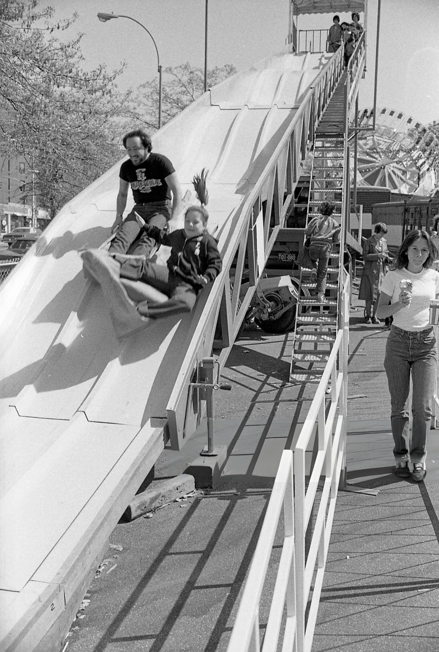 Two People Going Down A Slide At The Resurrection Ascension Church Carnival In Rego Park, Queens, 1979.