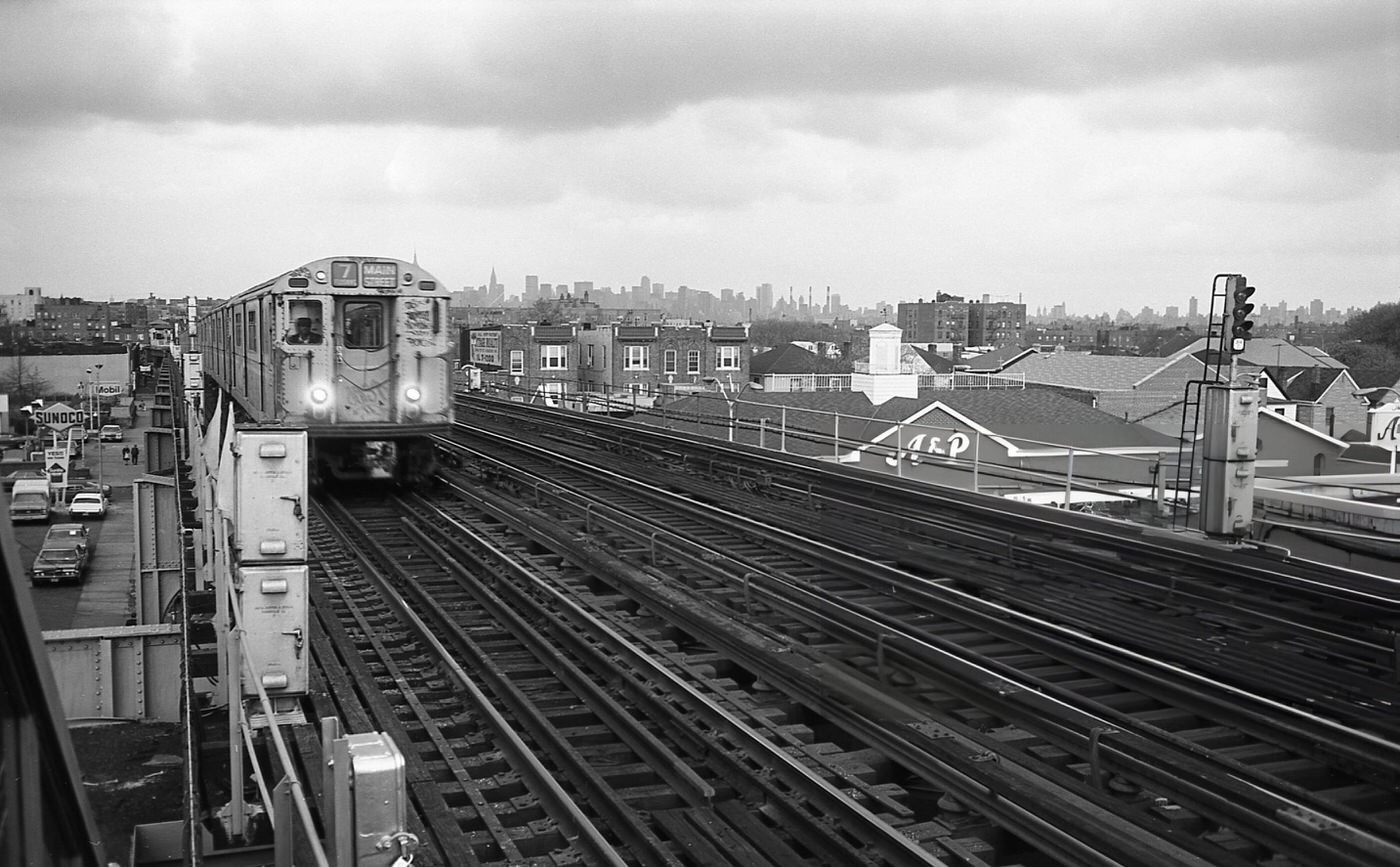 The Number Seven Train Pulls Into The Elevated Subway Station At 103Rd Street In Corona, Queens With The New York City Skyline Visible In The Background, 1970S.