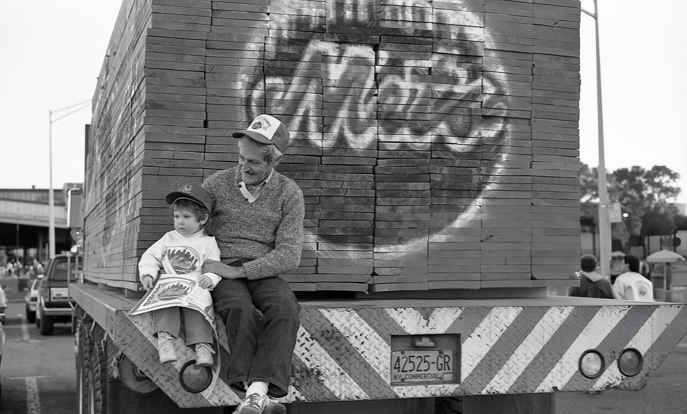 A Man And A Young Boy Sit On The Flatbed Of A Lumber Truck Parked Outside Shea Stadium Before Game Six Of The 1986 World Series, Corona, Queens, 1986.
