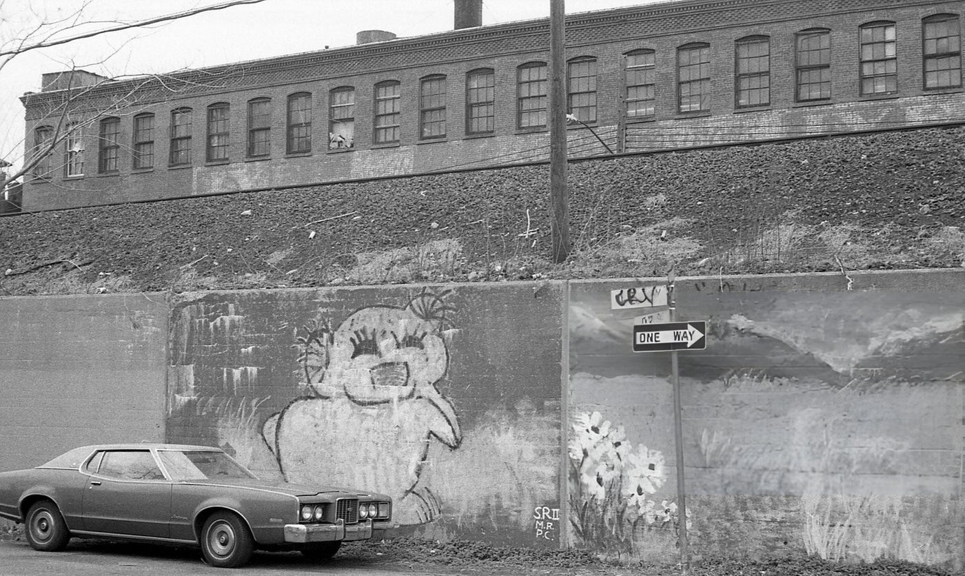 A Vehicle Parked Next To A Retaining Wall Covered In Street Art In Corona, Queens, 1982.
