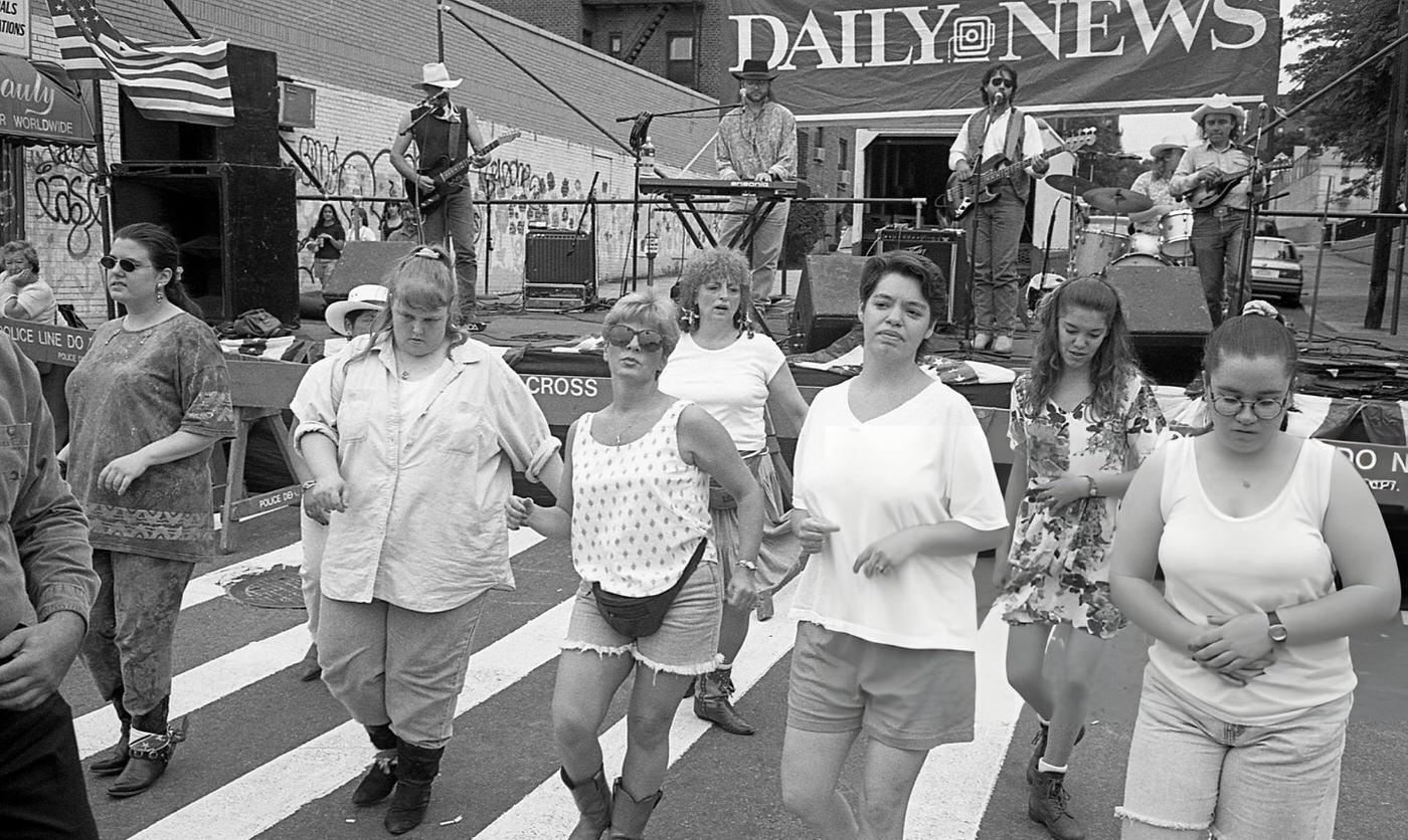 People Line Dancing As A Band Performs On Stage On 63Rd Drive During The 63Rd Drive Street Fair In The Rego Park Neighborhood, Queens, 1995.
