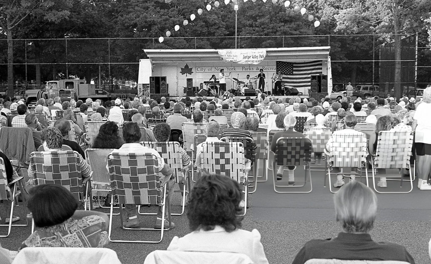 Audience Members Sitting In Chairs Watching A Band Perform On Stage At A Free Concert In Juniper Valley Park In Queens' Middle Village Neighborhood, 1997.