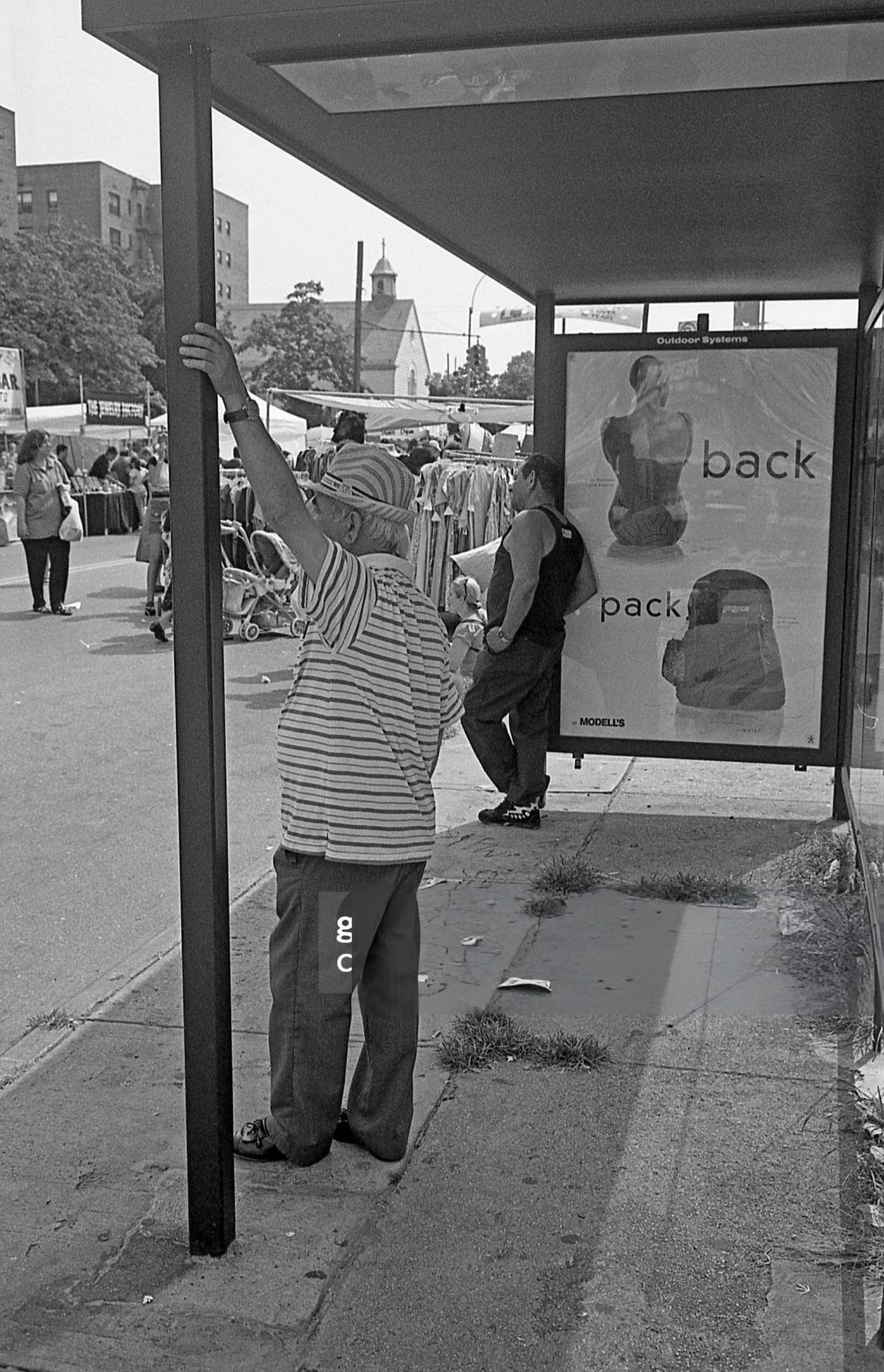 Two Men Stand At A Bus Stop On 63Rd Drive During The 63Rd Drive Street Fair, Rego Park, Queens, 1997.