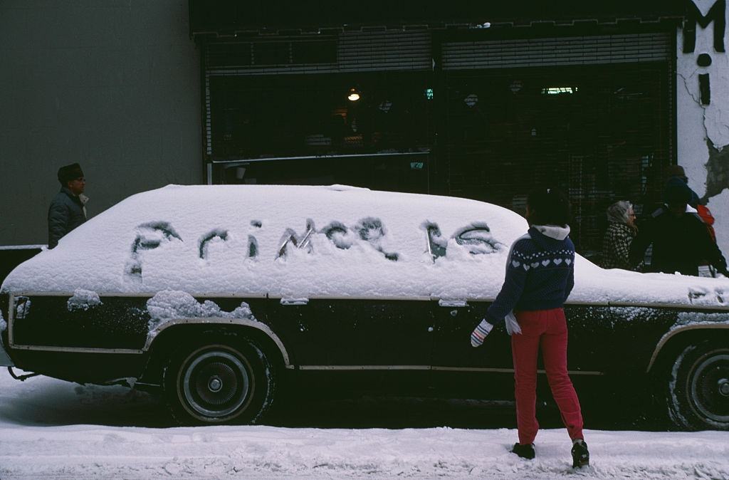 A Girl Writing In The Snow Covering A Car In New York City, During The Blizzard Of January 1996.