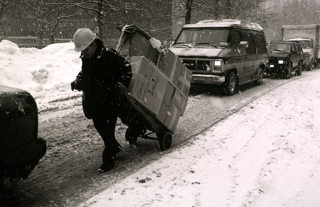 A Delivery Of Goods Is Pulled By Hand In The Middle Of Snow Bound Traffic, 1996