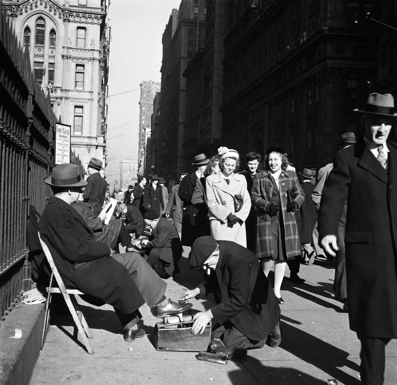 New Yorkers Walk On Broadway As Men Get Their Shoes Waxed Along The Gates Of Trinity Church, 1947.