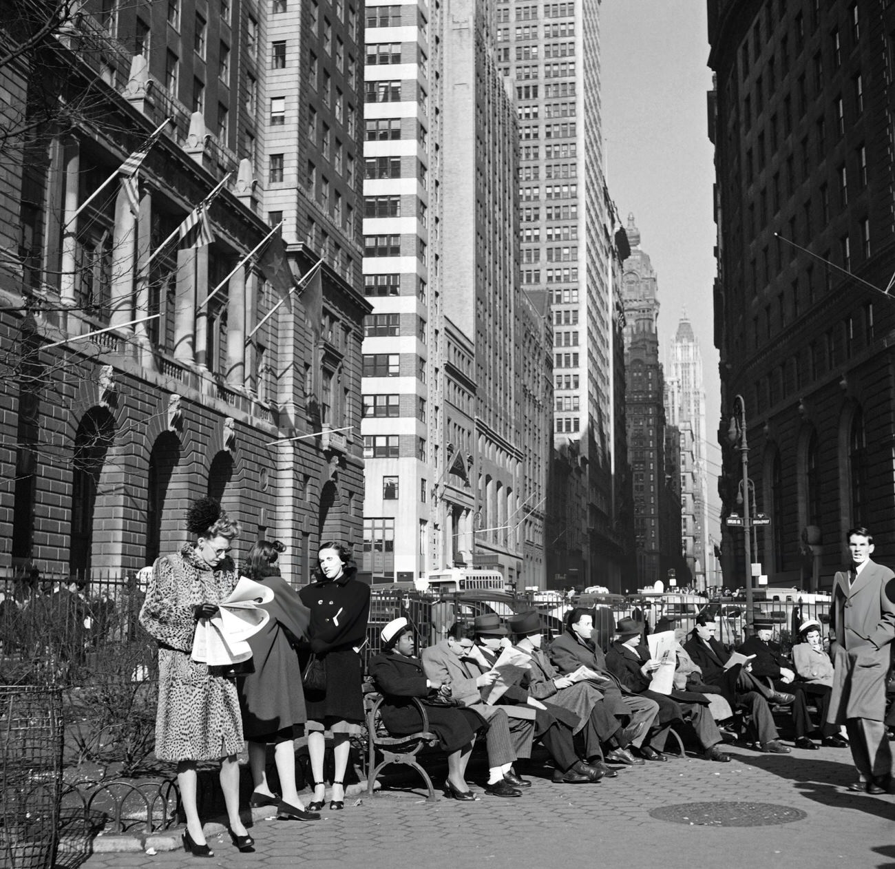 A Woman Reads A Newspaper At Lunch Break While People Sit On The Benches Of Bowling Green Park, 1947.