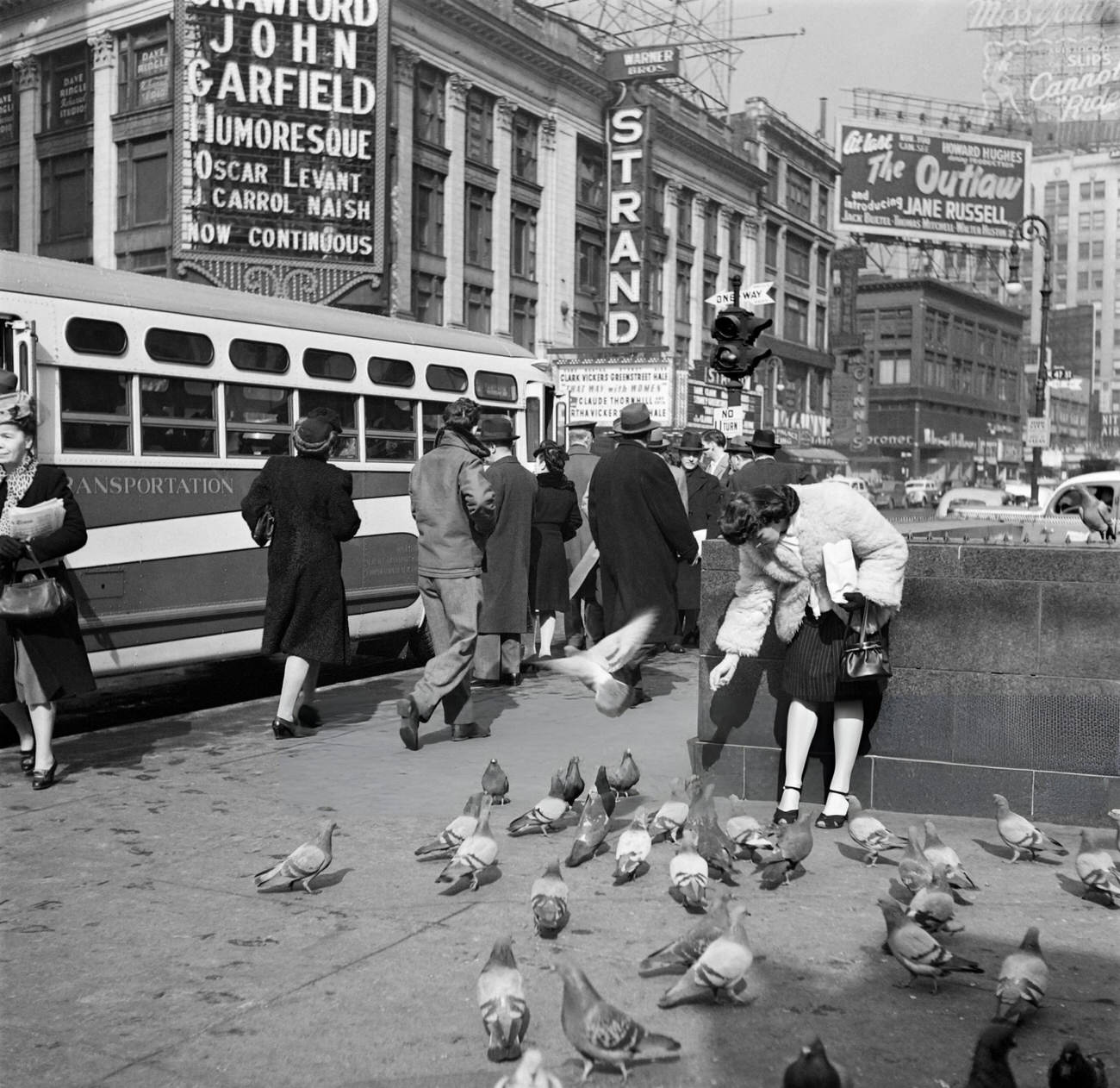 A Young Woman Feeds Pigeons At A Bus Stop Near The Strand Theatre, 1947.