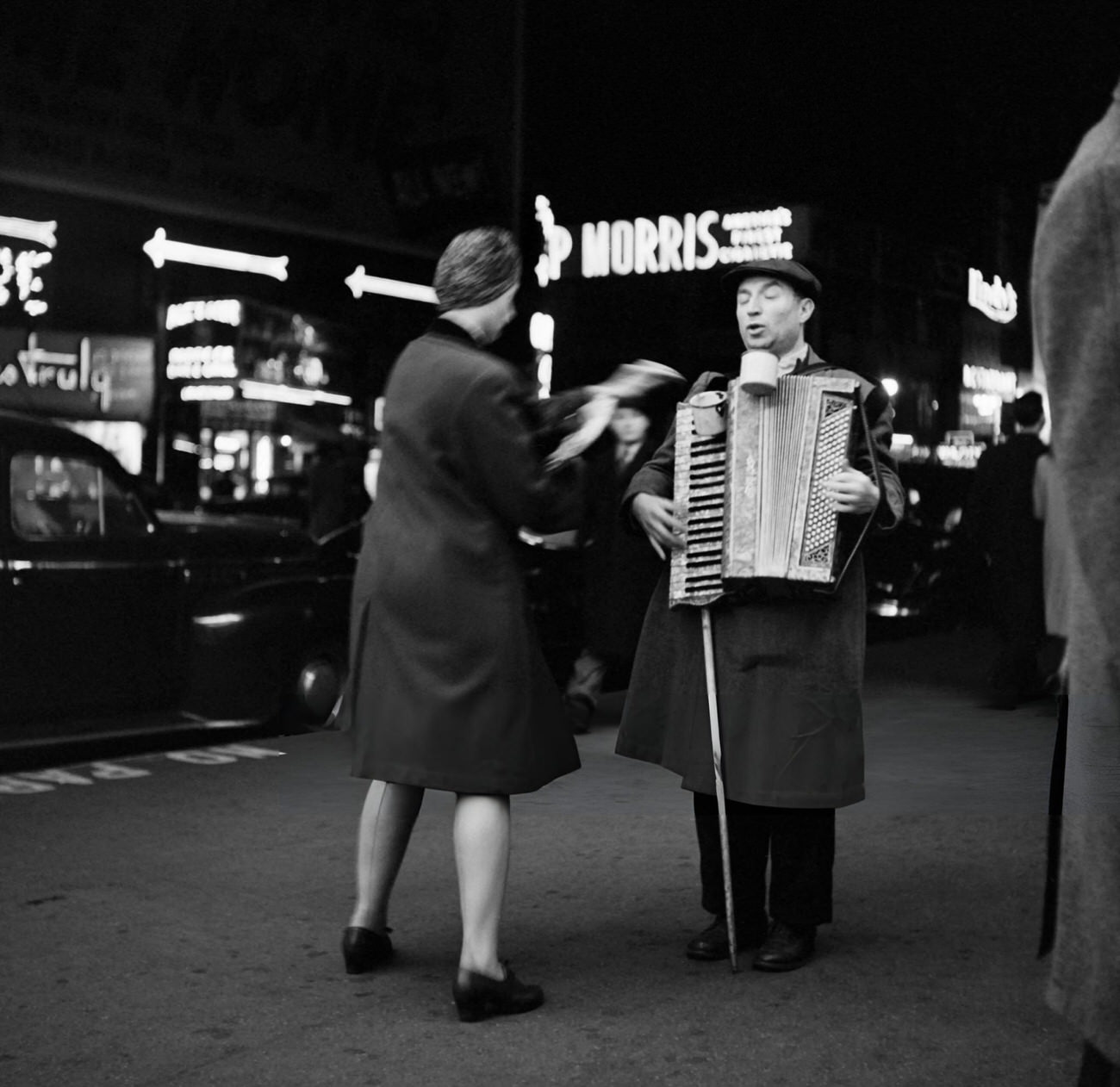 A Woman Gives Money To A Blind Accordionist Who Plays On Broadway At Night, 1947.