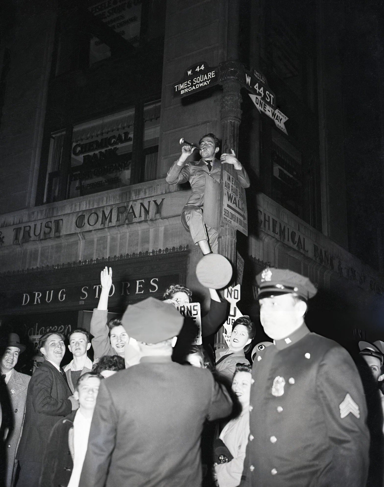 A Man On A Street Sign Post With A Party Favor During A V-E Day Celebration In Times Square, 1945.