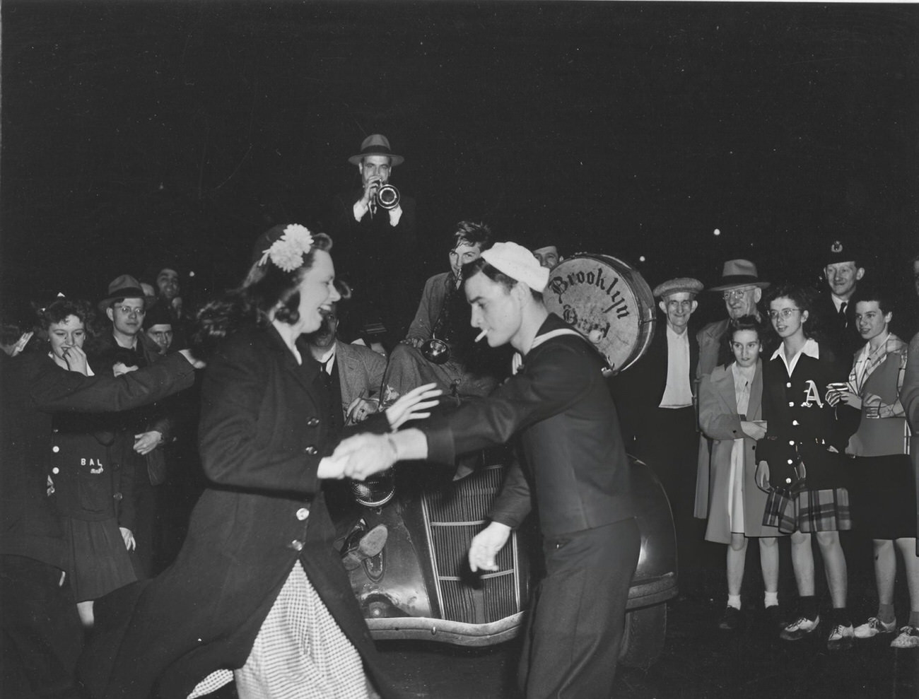 A Sailor Dances With A Laughing Woman In Times Square As A Brass Band Plays On The Hood Of A Car In Celebration Of Ve Day, 1945.