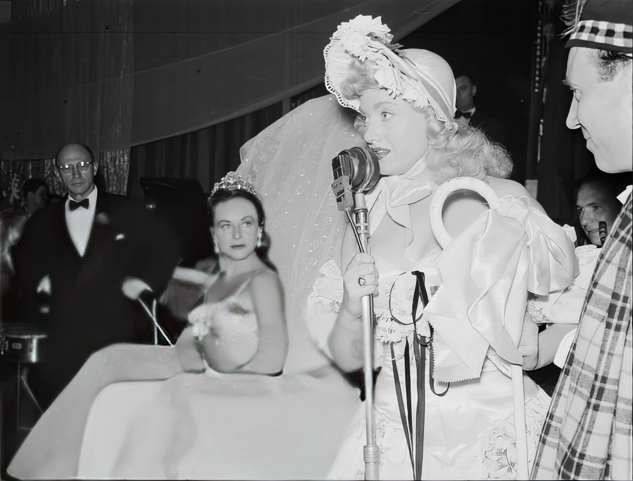 A woman dressed as Little Bo Peep speaking into a microphone, 1951.