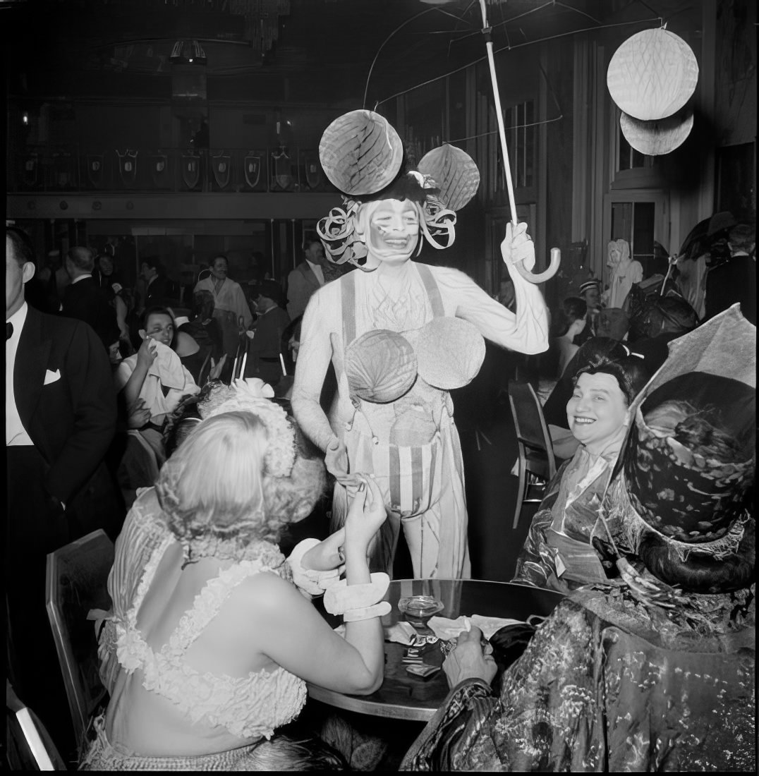 A costumed person entertaining a table of women, 1951.