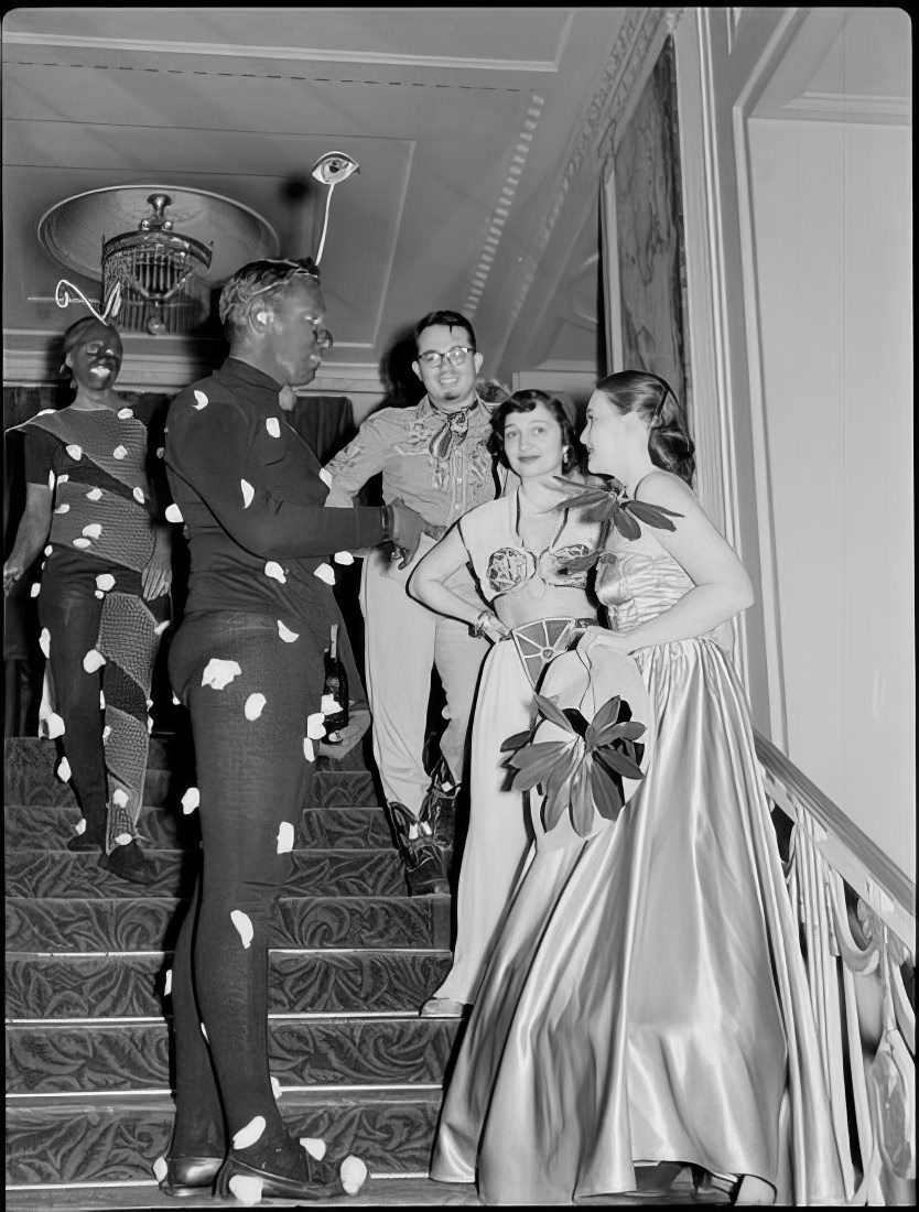 A group of costumed people talking on stairs, 1951.