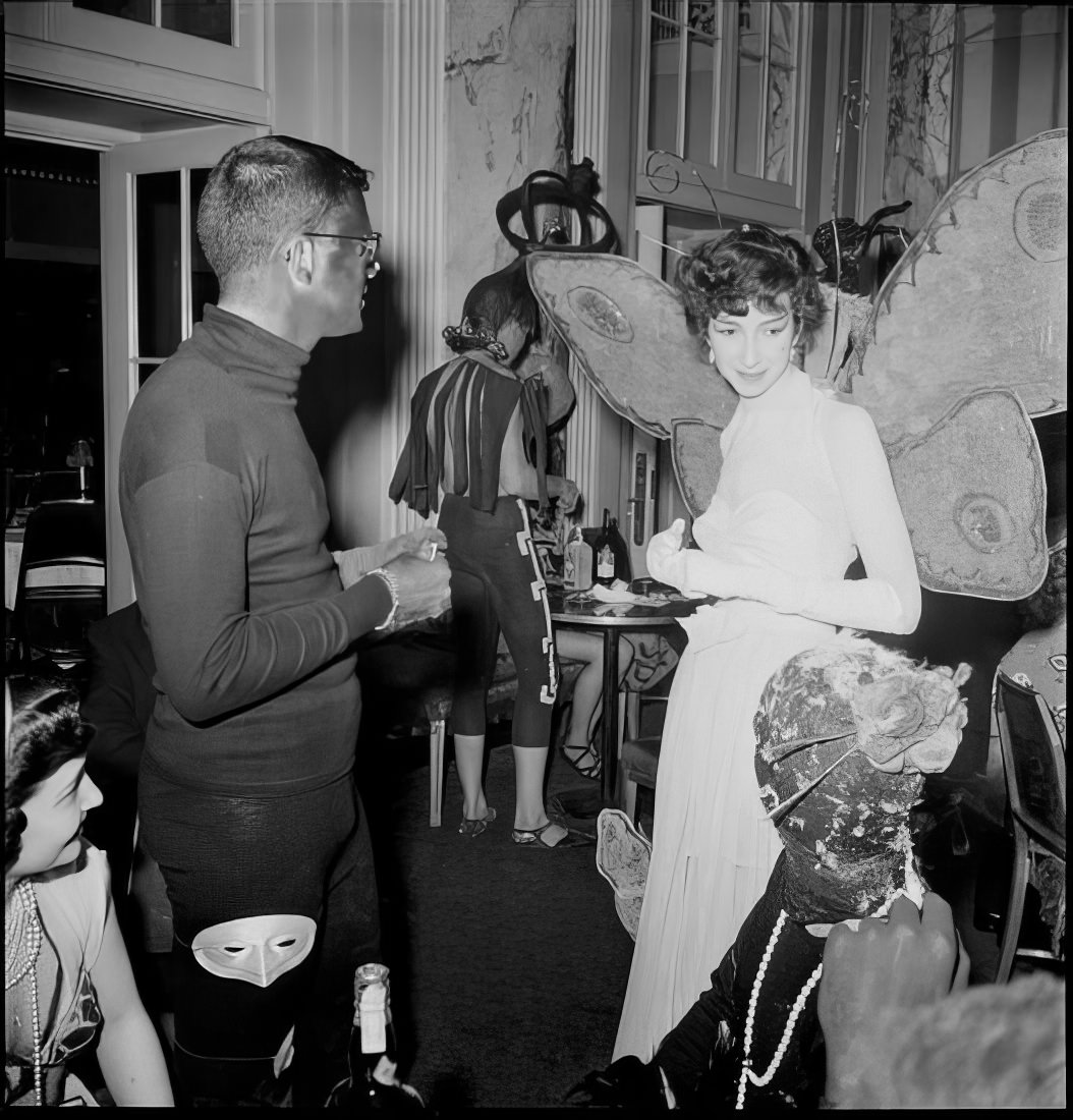 A man talking to a woman wearing butterfly wings, 1951.