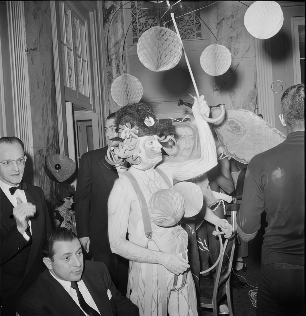 A costumed person with balloons marching around men in suits, 1951.