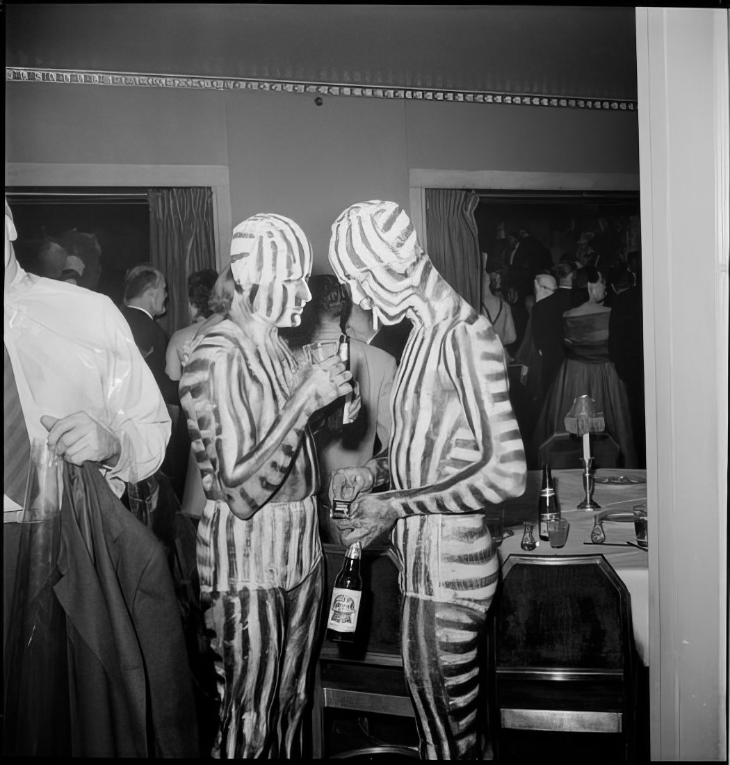 Men in matching body paint smoking and holding bottles of beer, 1951.