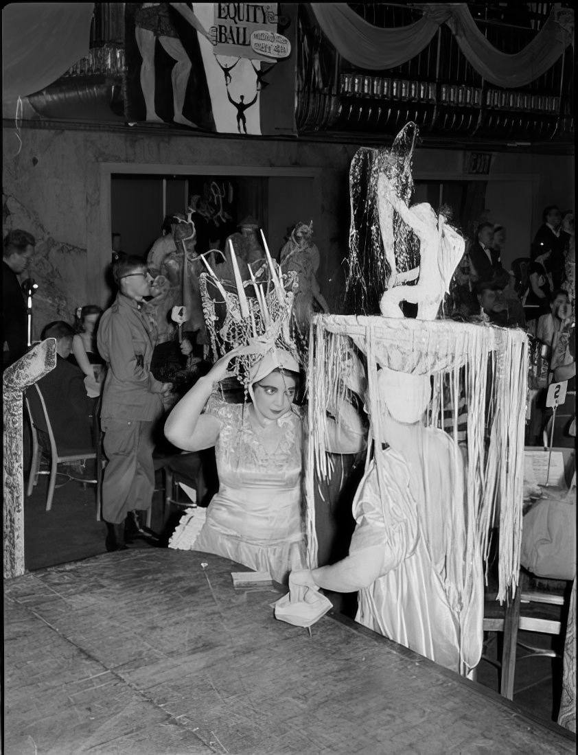 Two people in elaborate costumes talking, 1951.