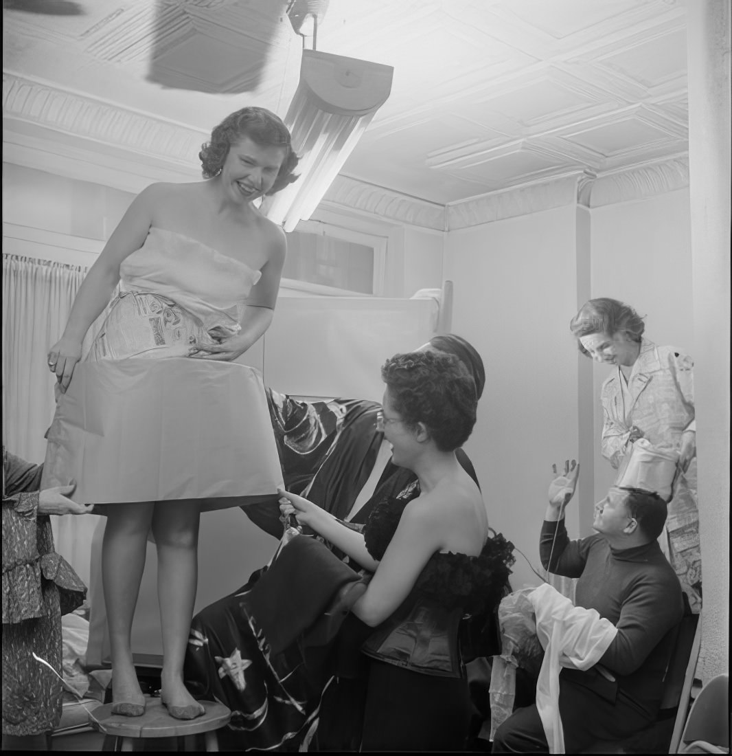 A woman putting on her costume as others make adjustments to their costumes, 1951.