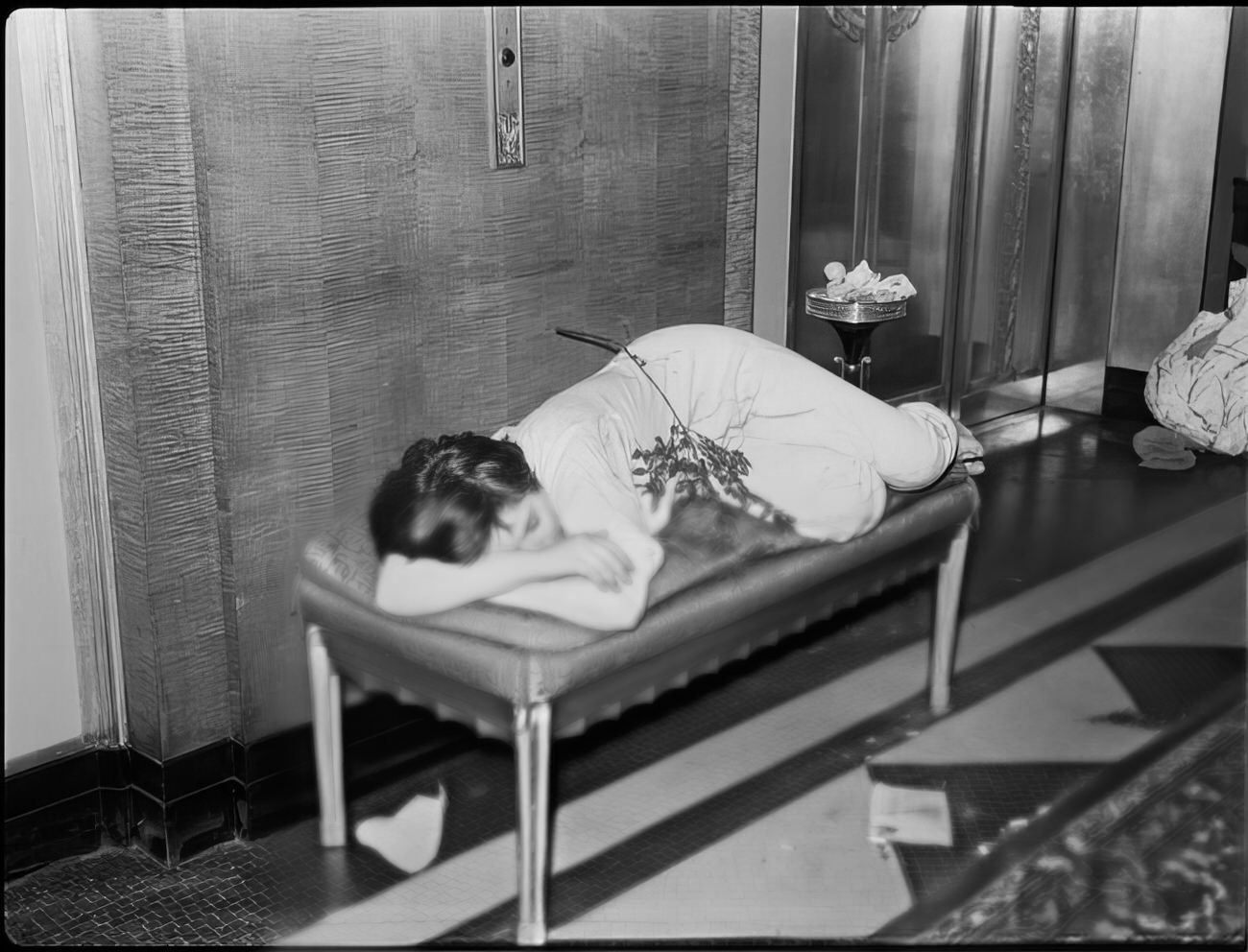 A woman sleeping on small couch by the elevators, 1951.