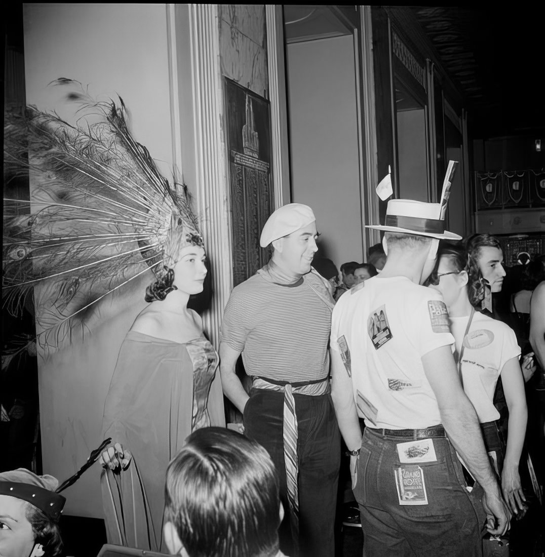 A woman wearing an elaborate headpiece with a group of other costumed ball guests, 1951.