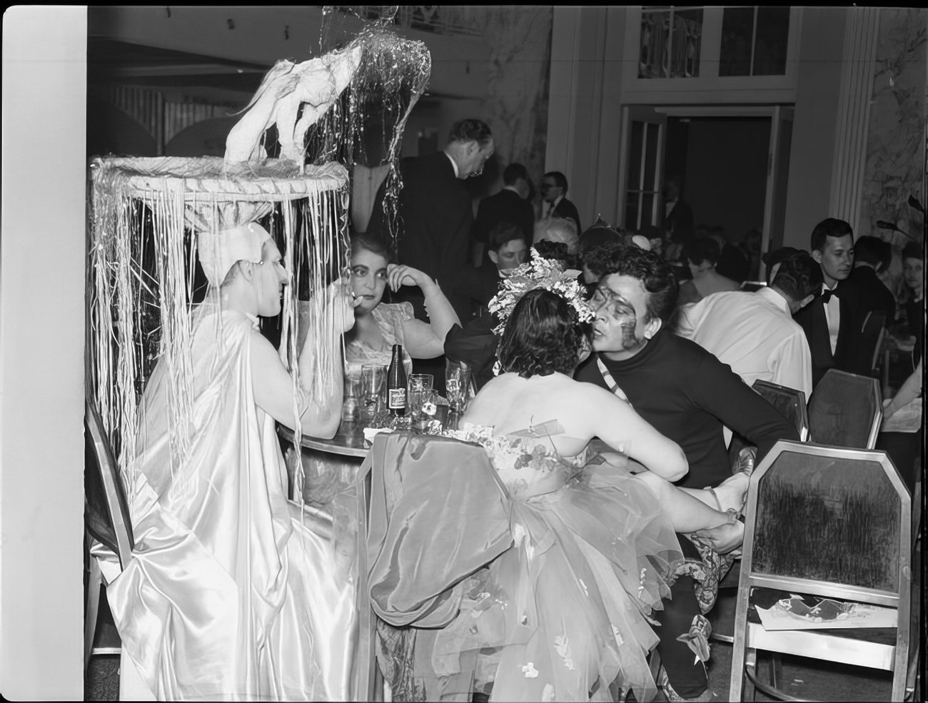 A group in elaborate costumes sitting at a table, 1951.