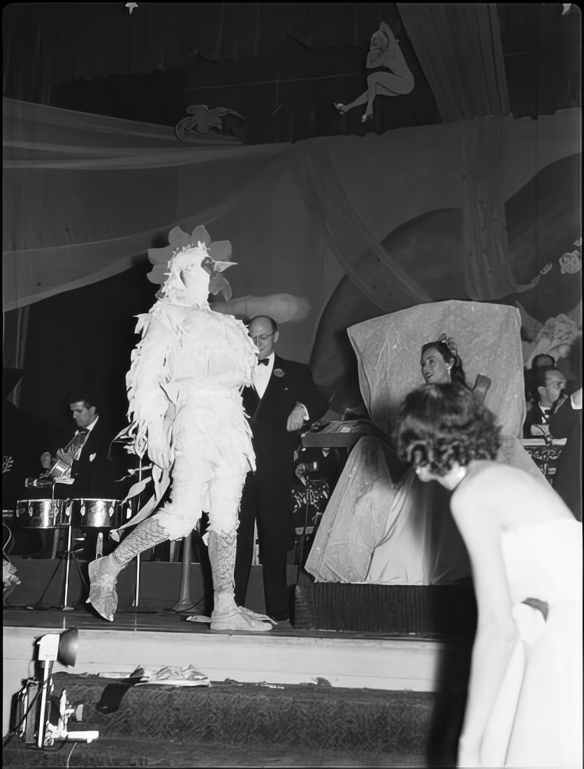 A man dressed as a chicken walking across the stage, 1951.