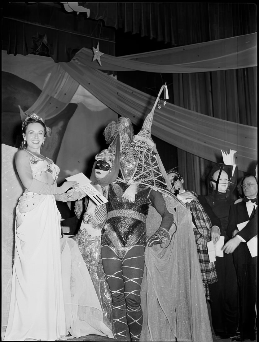 A woman giving a couple the 11th place prize for best costume, 1951.