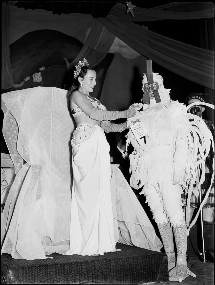 A woman giving a man the 7th place prize for best costume, 1951.