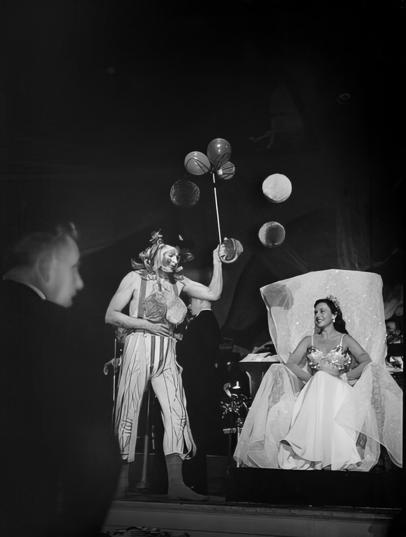 A woman watching another woman walk across the stage with balloons, 1951.