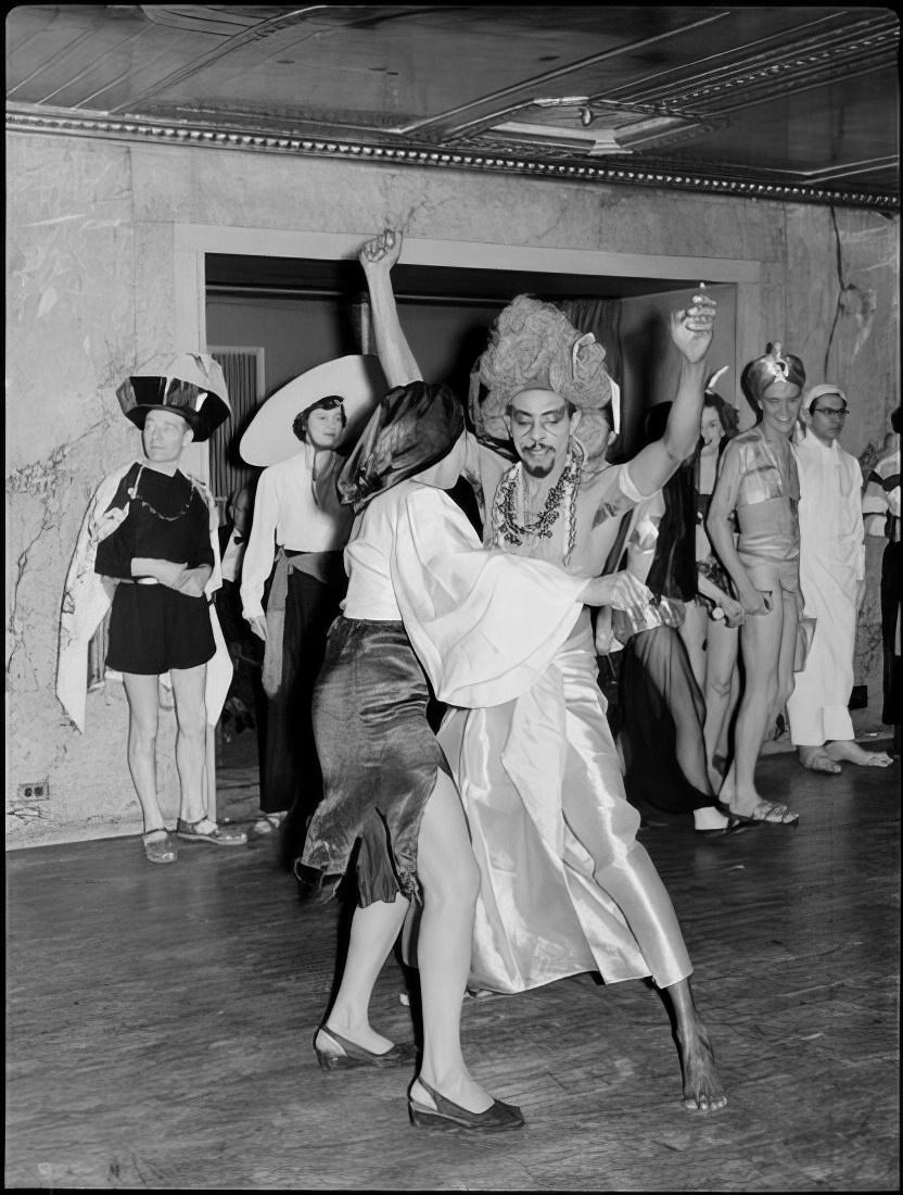 A costumed couple dancing as other guests watch, 1951.