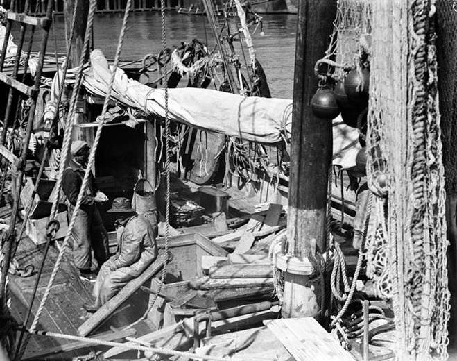 Waterfront scene with two men on a boat, 1937.