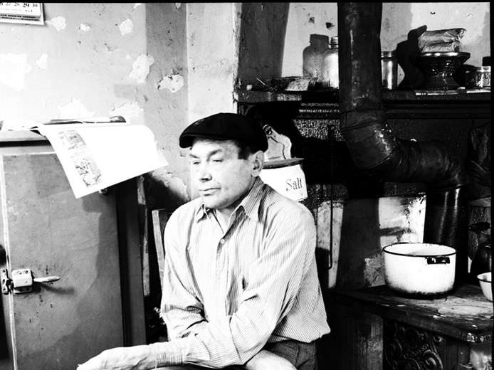 Man seated near an old stove, 1935.