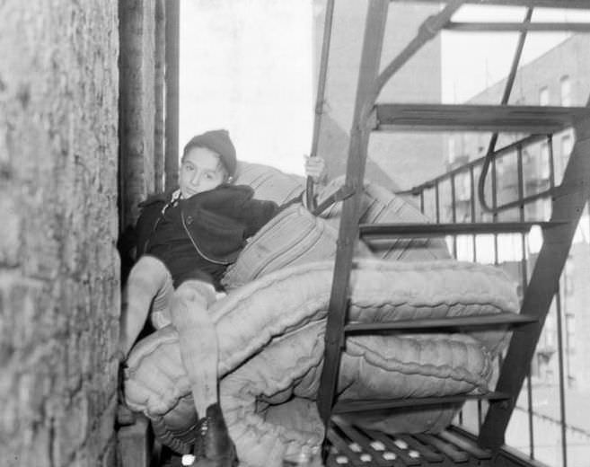 Boy on a fire escape with a mattress, 1935.