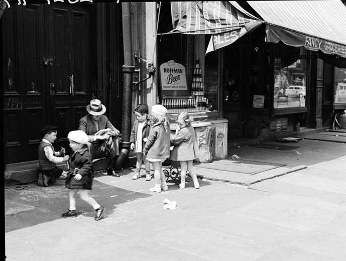 Children on a sidewalk; man sitting on a step, 1935.