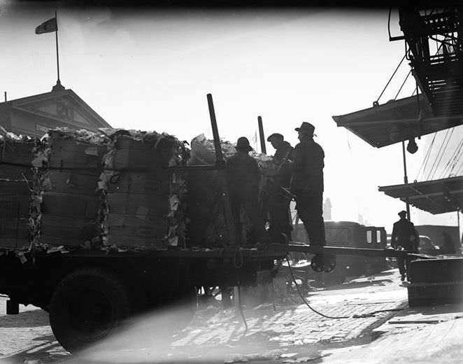 Waterfront scene with a cart loaded with garbage bales, 1937.