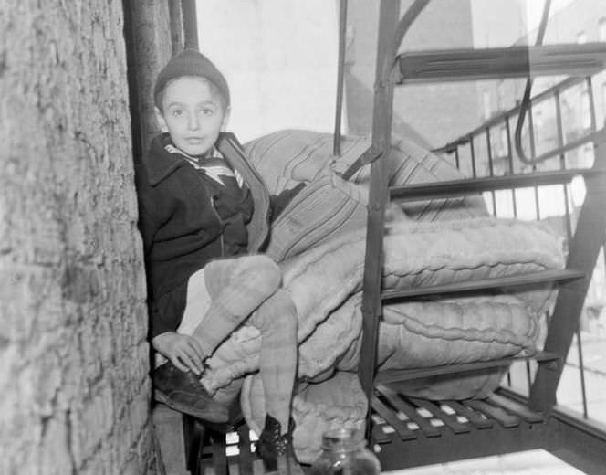 Boy and mattress on fire escape, 1936