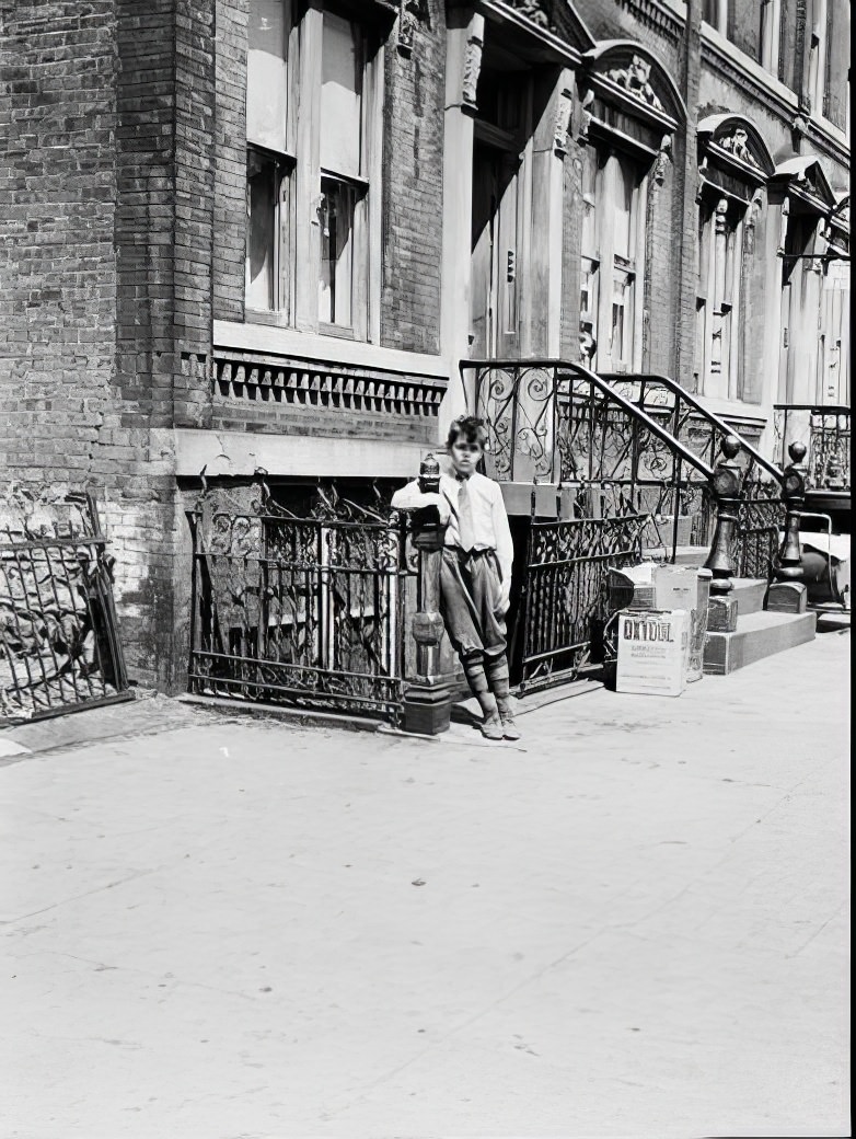 Boy leaning on ironwork fence, 1935