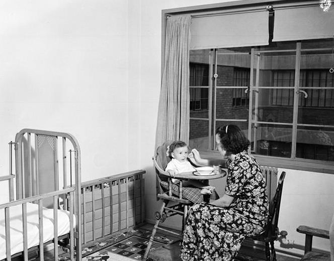 Feeding baby in high chair, 1935