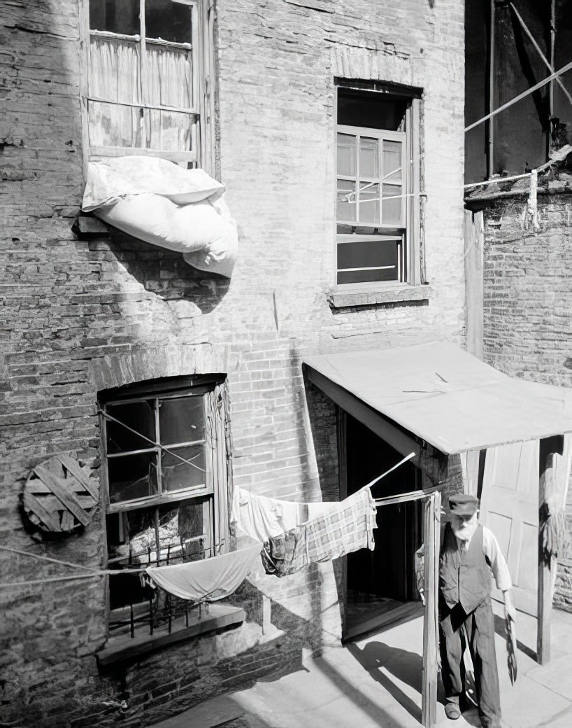 Tenement rear with man in doorway, 1936.