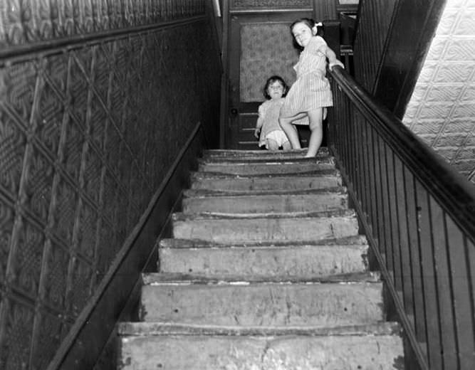 Two children on shabby staircase, 1935.