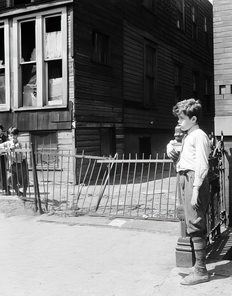 Boy standing by a rickety picket fence, 1936.