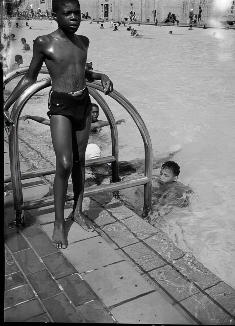 Boy standing by Colonial Park Pool, 1939.