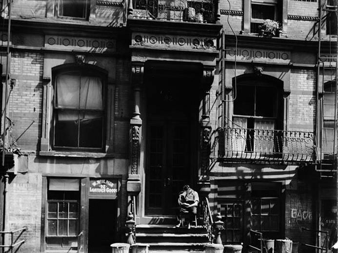 Slum front: man in chair on stoop, 1935.