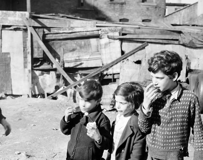 Children eating apples in front of a shack, 1936.