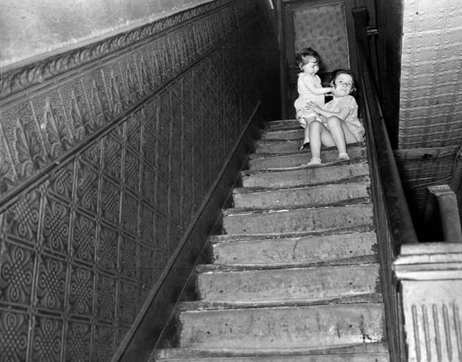 Children at the top of a shabby staircase, 1935.