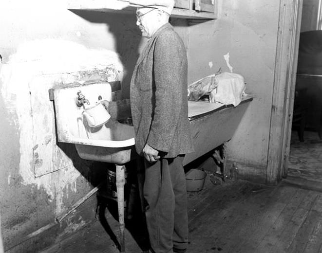 Man filling a pitcher at a sink, 1935.