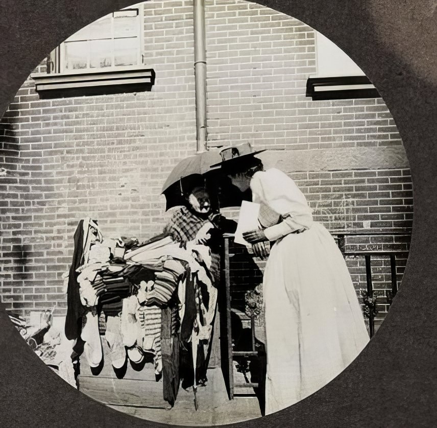 Woman street vendor with customer, circa 1895.