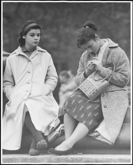 Two girls in coats sitting on the fountain steps, Washington Square Park, 1956.