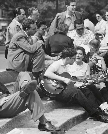 A girl in saddle shoes singing with a guitarist in Washington Square Park, 1956.